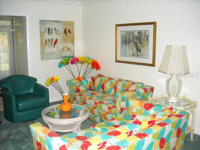 A living room features a patterned sofa, a teal armchair, and a glass-topped coffee table — 1700 GLENHOUSE DRIVE UNIT 305, SARASOTA, FL