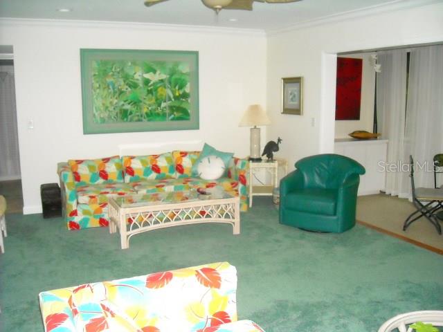 A living room features a colorful patterned sofa, a green armchair, and green carpeting — 1700 GLENHOUSE DRIVE UNIT 305, SARASOTA, FL