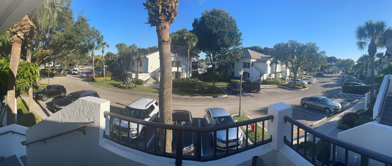 An elevated view of a residential parking lot surrounded by apartment buildings and palm trees — 7473 Glendevon Lane # 407, Delray Beach FL 33446, DELRAY BEACH, FL