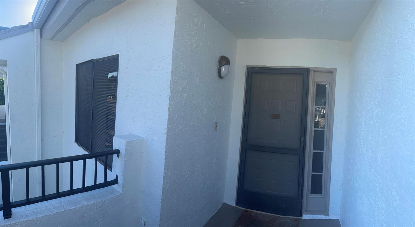 A hallway with wood-look flooring leads into a living area with a balcony view — 7473 Glendevon Lane # 407, Delray Beach FL 33446, DELRAY BEACH, FL