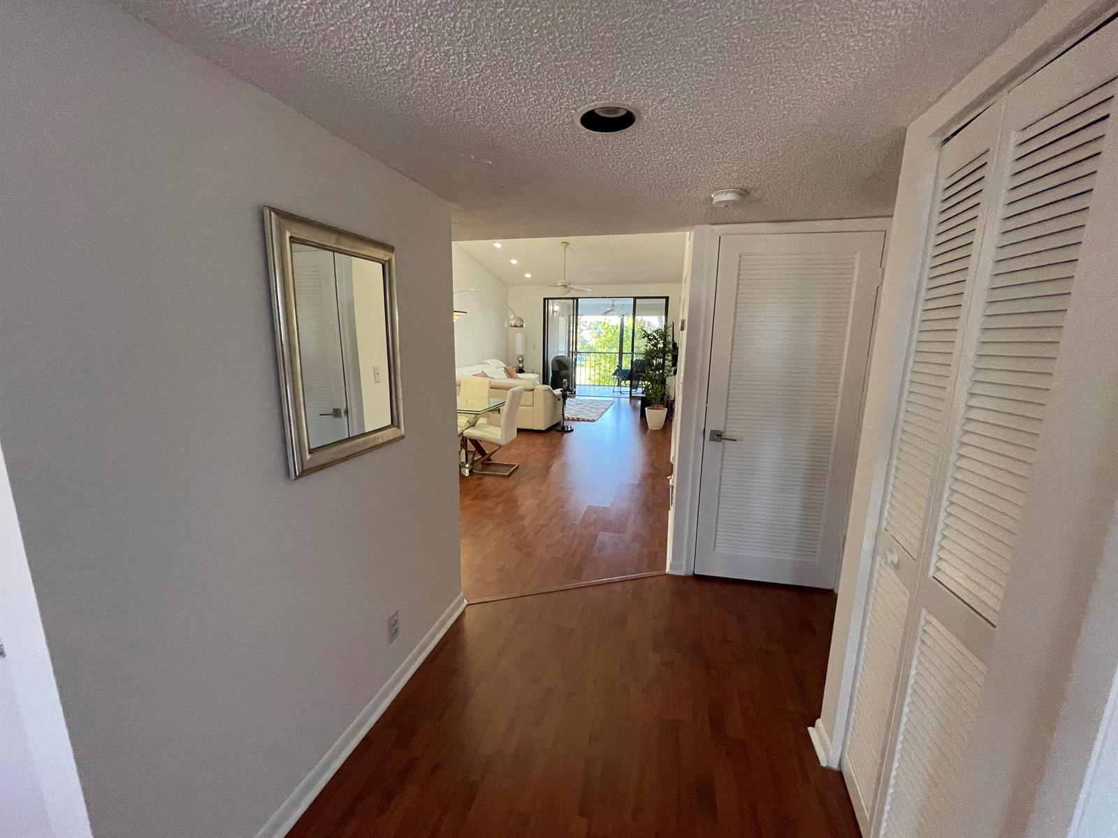 A modern kitchen features white cabinetry, stainless steel appliances, granite countertops, and dark wood flooring — 7473 Glendevon Lane # 407, Delray Beach FL 33446, DELRAY BEACH, FL