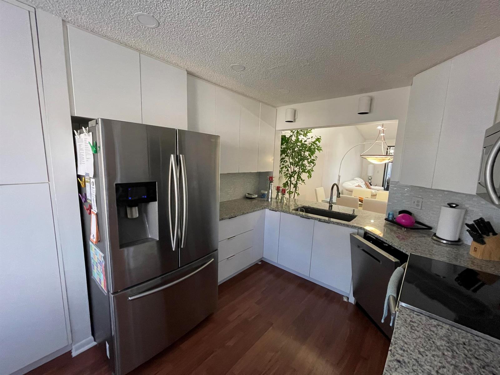A dining area features a glass table, four white chairs, tall cabinets, and a refrigerator — 7473 Glendevon Lane # 407, Delray Beach FL 33446, DELRAY BEACH, FL