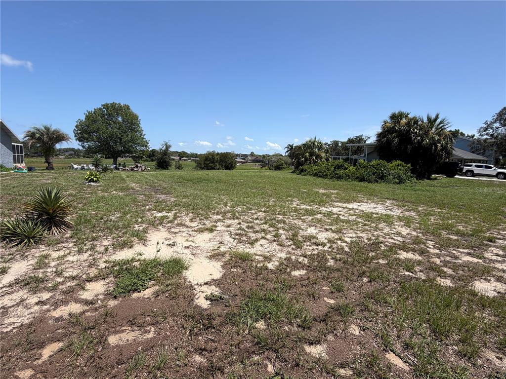 A large, grassy vacant lot with sandy patches under a clear blue sky — 5540 BAFFIN CIRCLE, SPRING HILL, FL