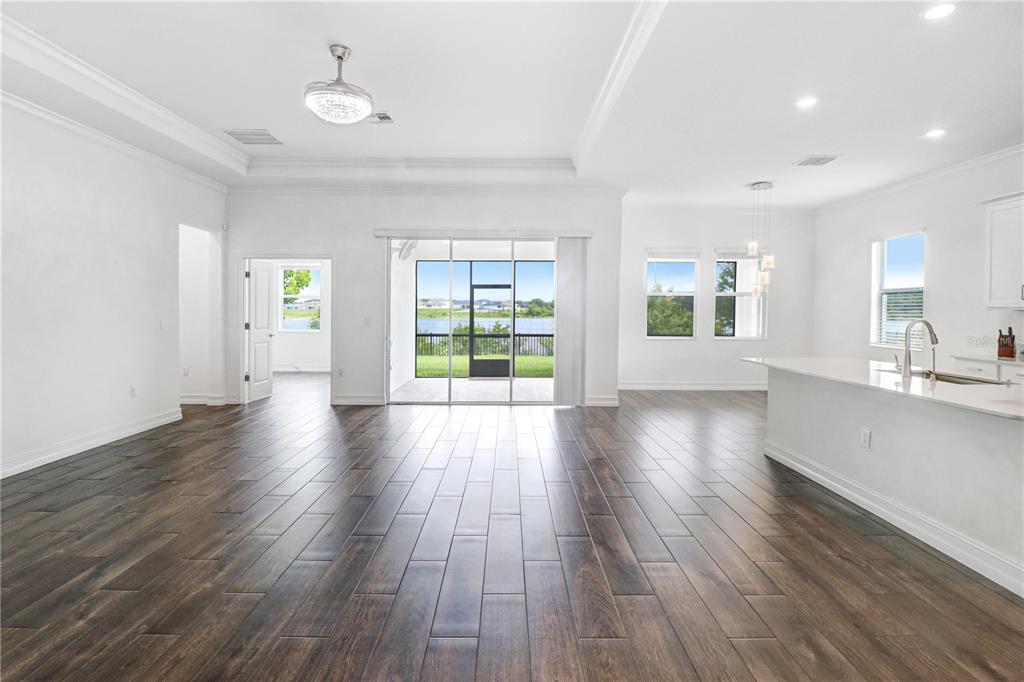 An open-concept living area with dark wood-look tile floors, white walls, and a lake view — 12876 BERGSTROM BAY DRIVE, RIVERVIEW, FL
