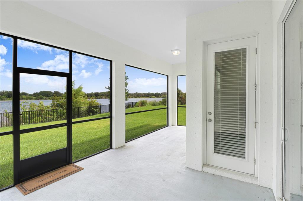 A screened-in porch with a concrete floor overlooks a grassy lawn and a lake — 12876 BERGSTROM BAY DRIVE, RIVERVIEW, FL