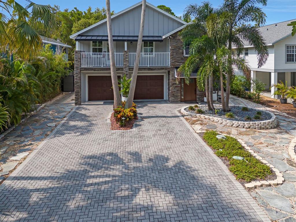 A two-story house with a stone facade, a paved driveway, and palm trees in front — 940 WISCONSIN AVENUE, PALM HARBOR, FL