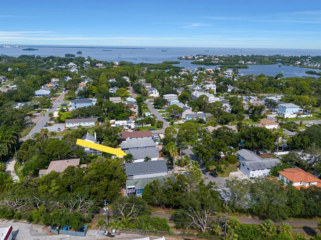 An aerial view shows a residential neighborhood with houses, trees, and a body of water — 940 WISCONSIN AVENUE, PALM HARBOR, FL