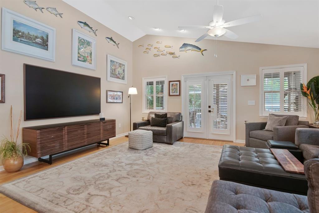 A living room features a large television, neutral walls with fish decor, and gray furniture — 940 WISCONSIN AVENUE, PALM HARBOR, FL