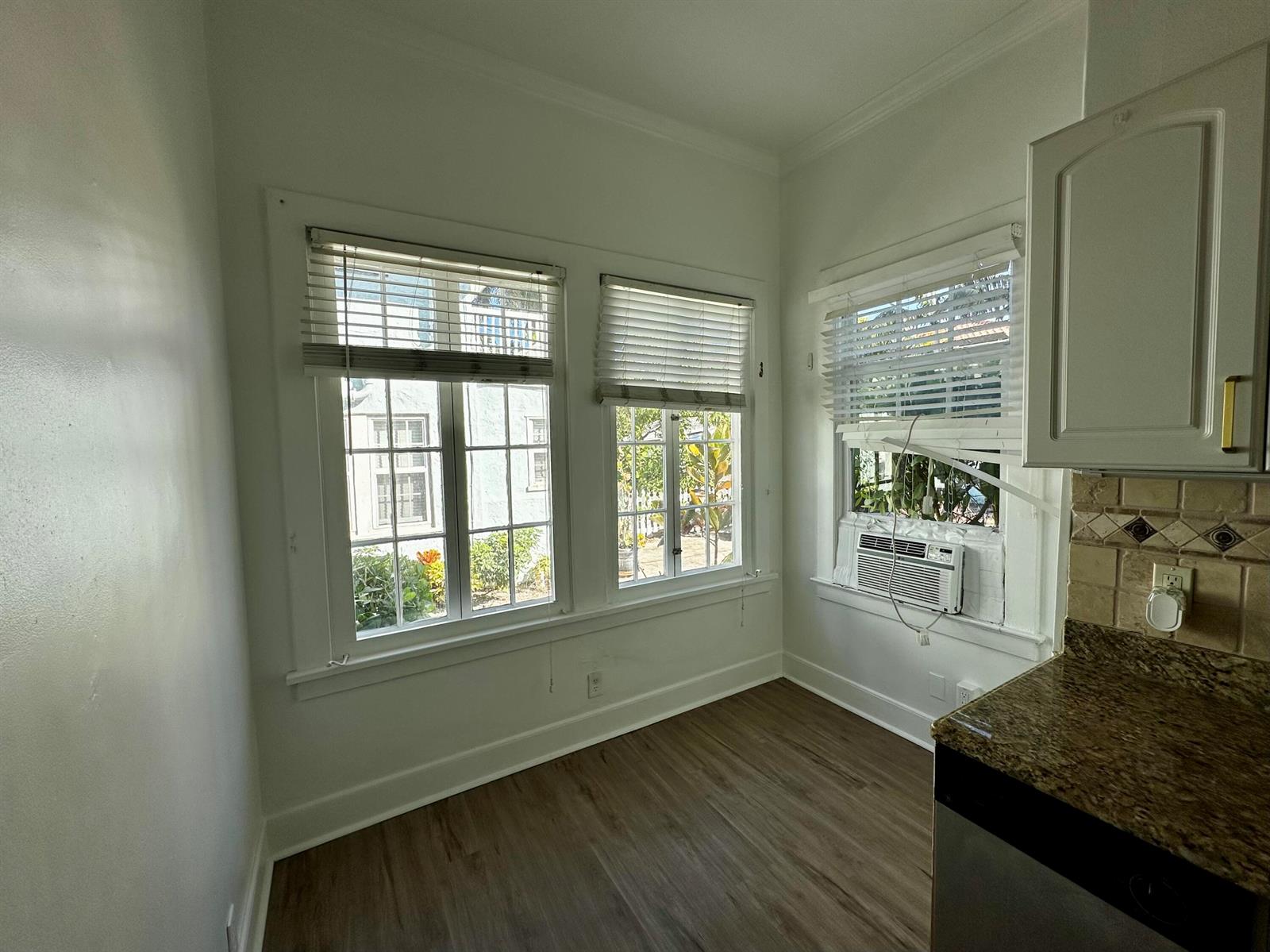 A kitchen nook features wood-look flooring, white walls, three windows with blinds, and an air conditioner — 270 Seminole Avenue # 3, Palm Beach FL 33480, PALM BEACH, FL