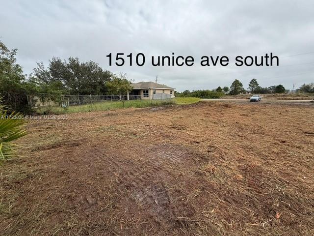 A cleared, dirt-covered vacant lot sits in front of a single-story house under a cloudy sky — 1510 Unice AVE S, Lehigh Acres FL 33976, LEHIGH ACRES, FL