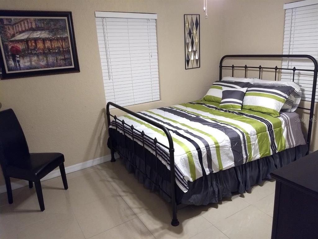 A bedroom features a black metal bed frame, striped bedding, a chair, and wall art — 2512 MUSSELWHITE AVENUE UNIT #1, ORLANDO, FL