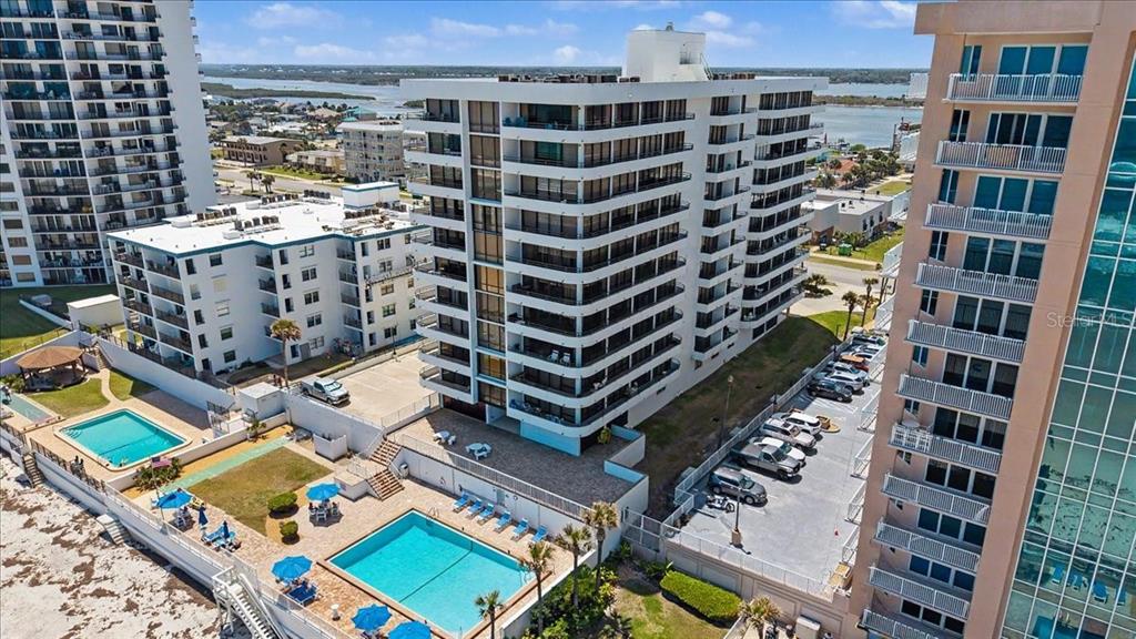 An aerial view of a multi-story apartment building with two swimming pools and parking lots — 3743 S ATLANTIC AVENUE UNIT 10B0, DAYTONA BEACH, FL