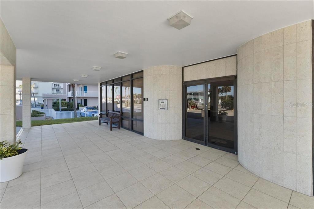 A covered outdoor entryway features tiled flooring, glass doors, and a bench — 3743 S ATLANTIC AVENUE UNIT 10B0, DAYTONA BEACH, FL