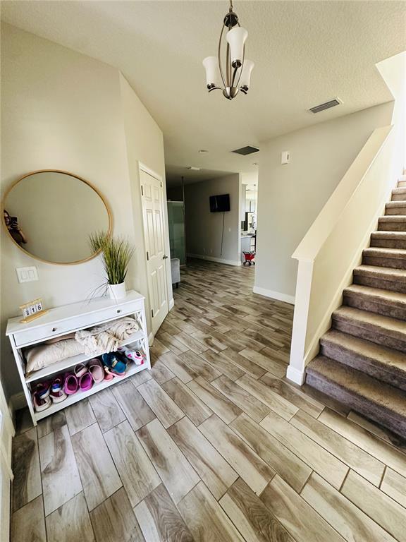 An entryway features wood-look tile flooring, a white console table, a round mirror, and stairs — 12990 BURNS DRIVE, ODESSA, FL