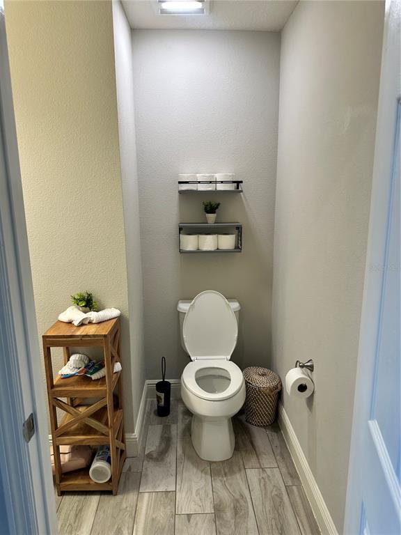 A small bathroom features a toilet, two wall-mounted shelves, and a wooden storage unit — 12990 BURNS DRIVE, ODESSA, FL