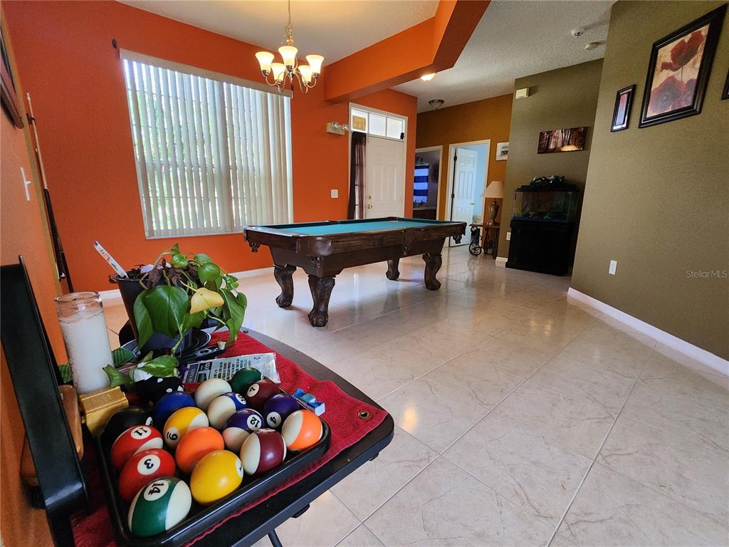 A room with tile flooring features a pool table, orange walls, and a billiard ball rack — 2503 BUTTERCUP COURT, KISSIMMEE, FL