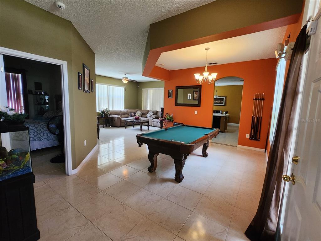 A pool table sits in a tiled room with orange walls and a vaulted ceiling — 2503 BUTTERCUP COURT, KISSIMMEE, FL