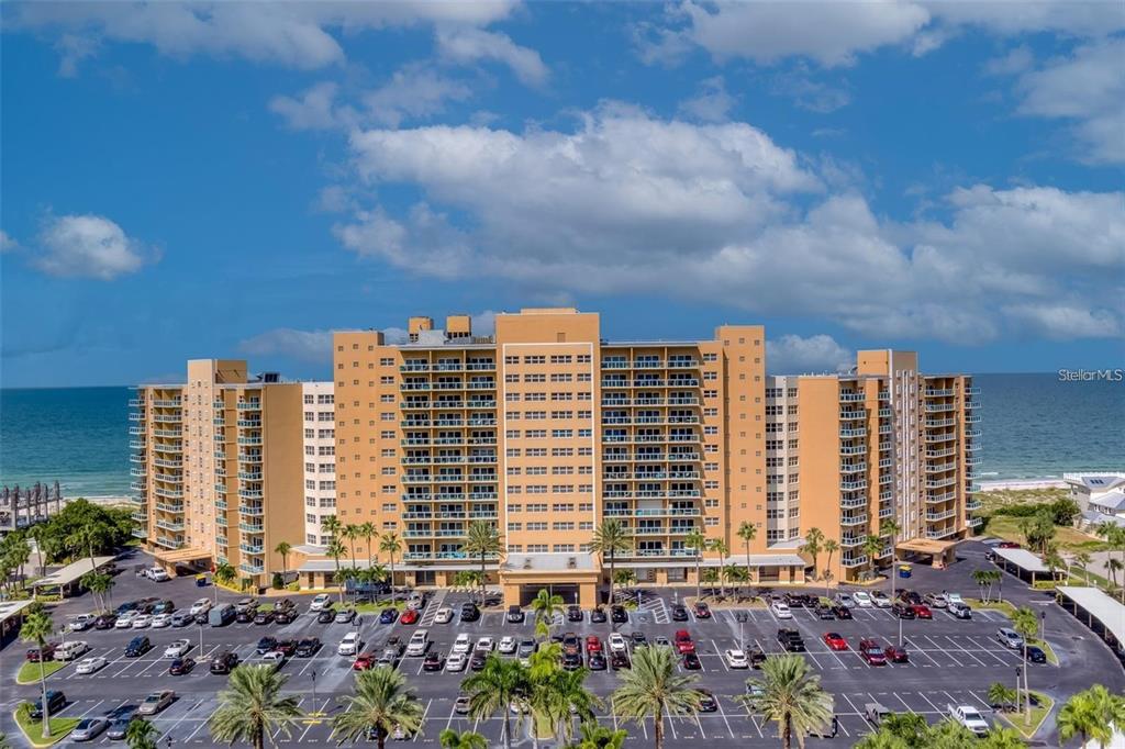 A large, multi-story tan apartment building sits directly on a sandy beach — 880 MANDALAY AVENUE UNIT S705, CLEARWATER, FL