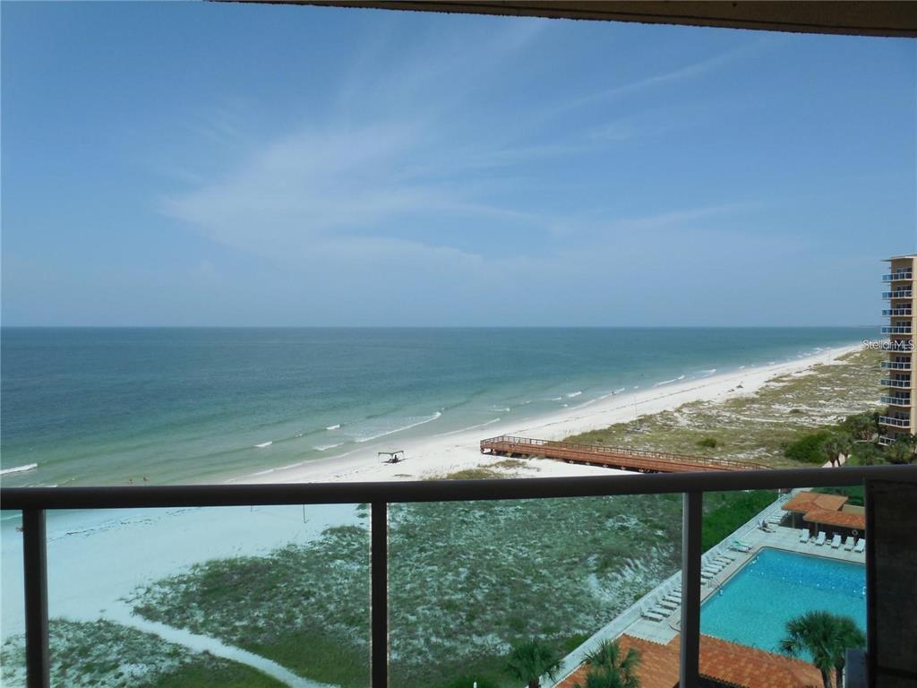 A high-angle view from a balcony overlooking a sandy beach, ocean, and swimming pool — 880 MANDALAY AVENUE UNIT S705, CLEARWATER, FL