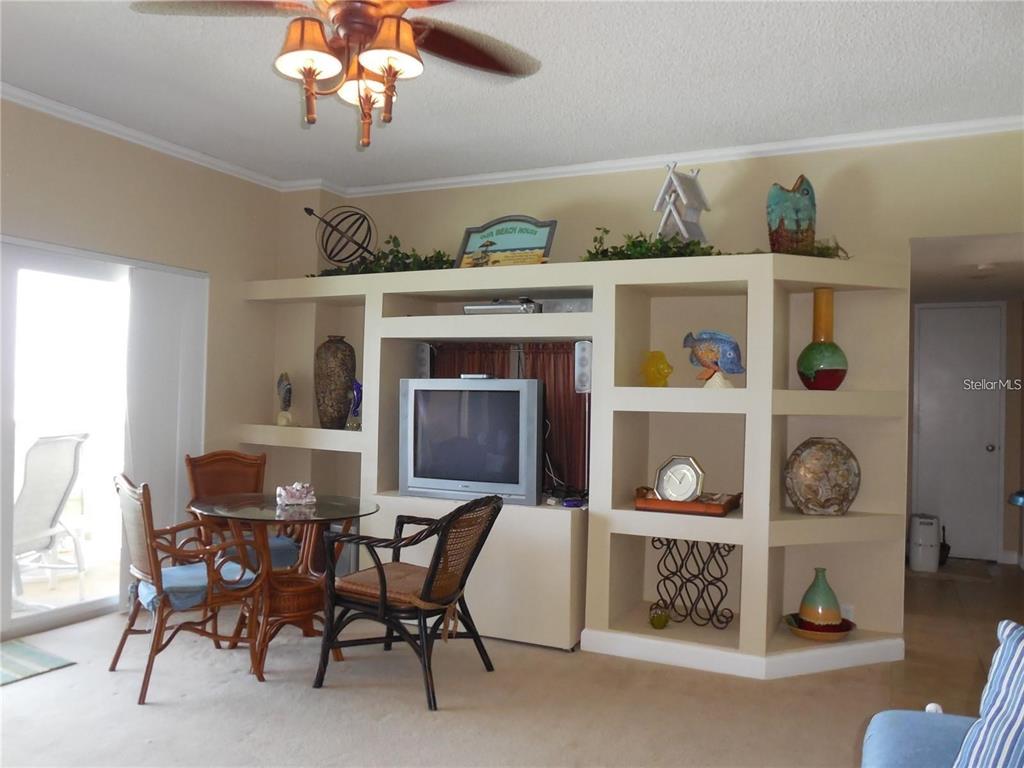 A living room features a large built-in entertainment center with open shelving and a dining set — 880 MANDALAY AVENUE UNIT S705, CLEARWATER, FL