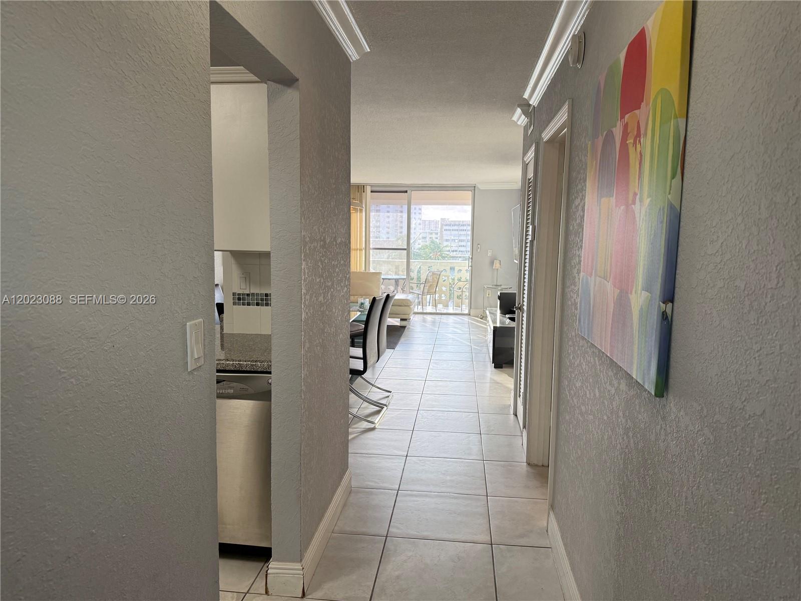 A tiled hallway leads past a kitchen into a living area with a balcony view — 1893 S Ocean Dr # 506, Hallandale Beach FL 33009, HALLANDALE BEACH, FL