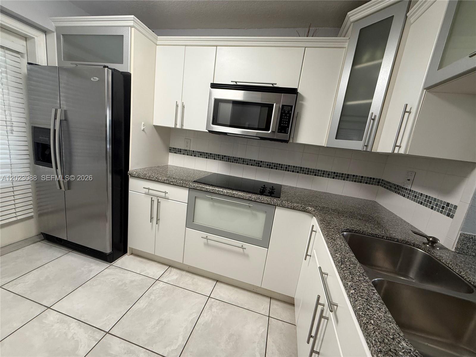 A kitchen features white cabinets, stainless steel appliances, granite countertops, and a tiled backsplash — 1893 S Ocean Dr # 506, Hallandale Beach FL 33009, HALLANDALE BEACH, FL