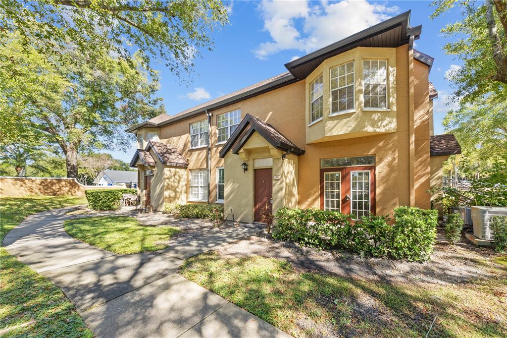 A two-story tan stucco townhouse with a sidewalk, landscaping, and a bay window — 6340 RALEIGH STREET UNIT 1011, ORLANDO, FL