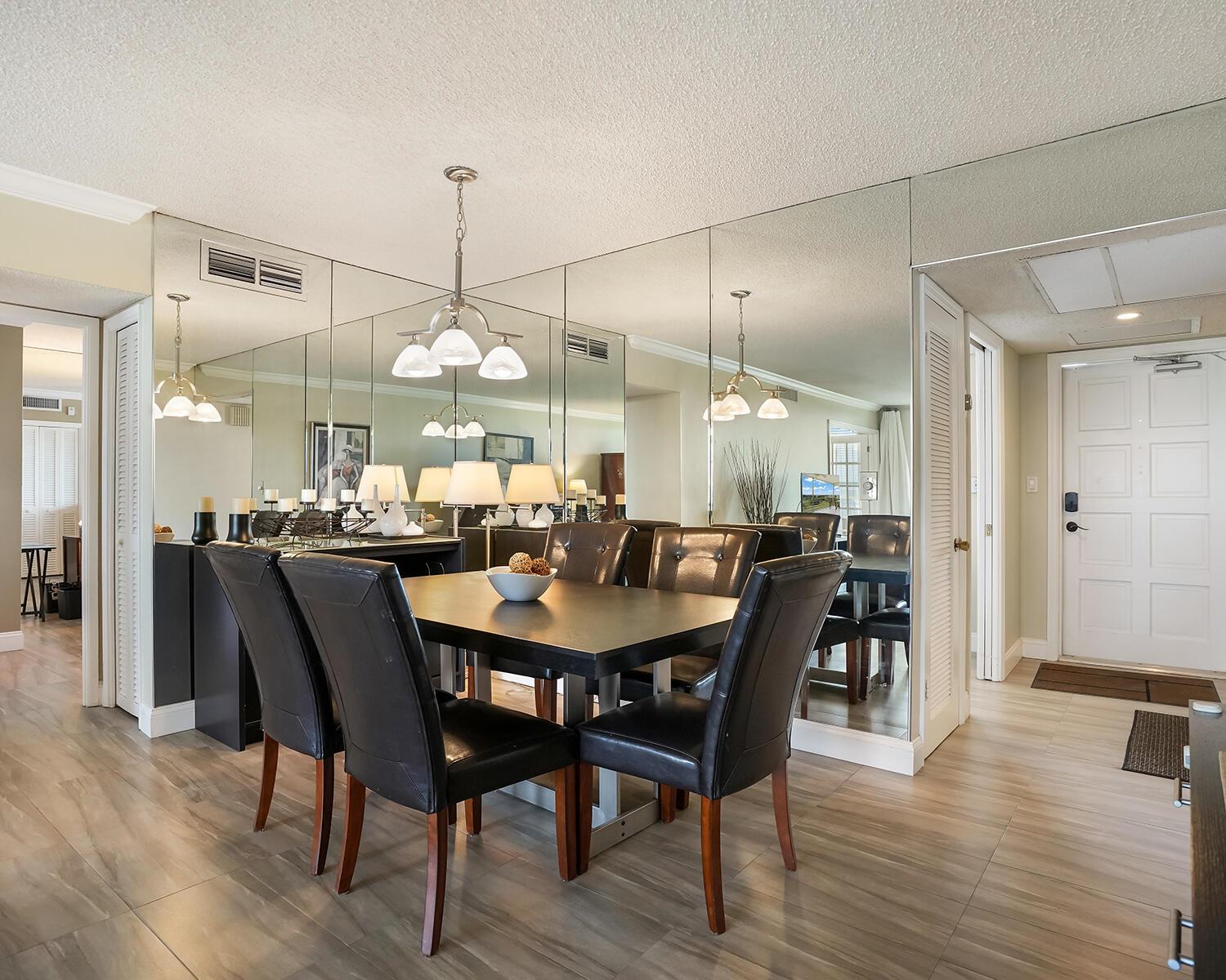 A dining room featuring a dark table, leather chairs, and a large mirrored wall — 2671 S Course Drive # 907, Pompano Beach FL 33069, POMPANO BEACH, FL