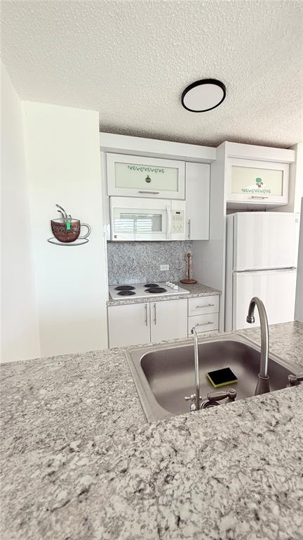 A kitchen features white cabinets, a microwave, a stove, a refrigerator, and granite countertops — AVENIDA MARINA VIEW DOS MARINAS II UNIT 908, FAJARDO, PR