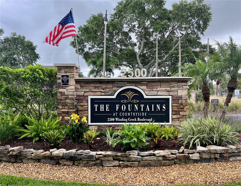A stone monument sign for The Fountains at Countryside stands in a landscaped garden — 2500 WINDING CREEK BOULEVARD UNIT C205, CLEARWATER, FL