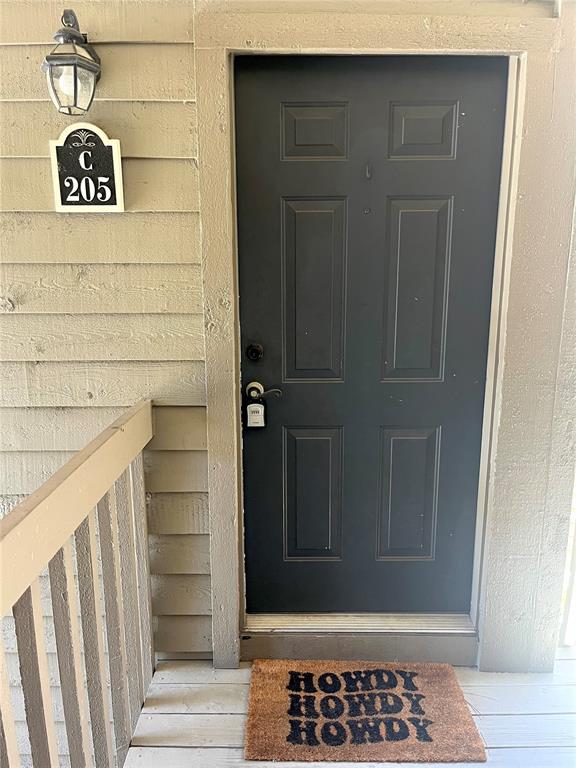 A dark-colored apartment door with a lockbox and a welcome mat on a porch — 2500 WINDING CREEK BOULEVARD UNIT C205, CLEARWATER, FL