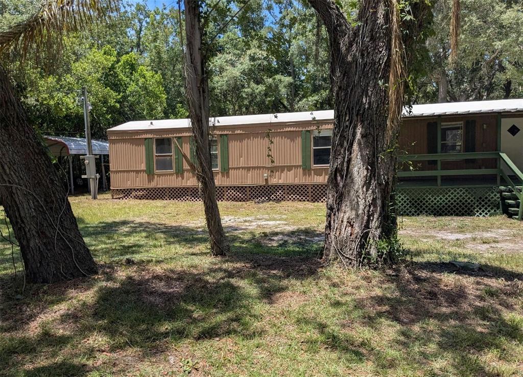 A brown mobile home features a covered front porch with green railings and stairs — 14737 BOLAND, SPRING HILL, FL
