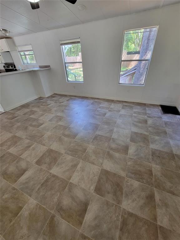 An empty room with light-colored walls, tile flooring, and two windows overlooking a backyard — 14737 BOLAND, SPRING HILL, FL