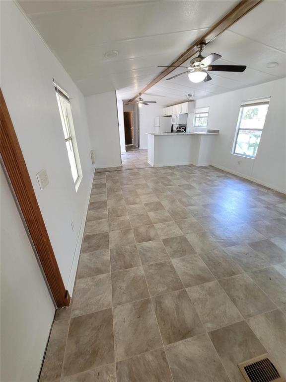 A tan mobile home with green shutters sits in a wooded yard with large trees — 14737 BOLAND, SPRING HILL, FL