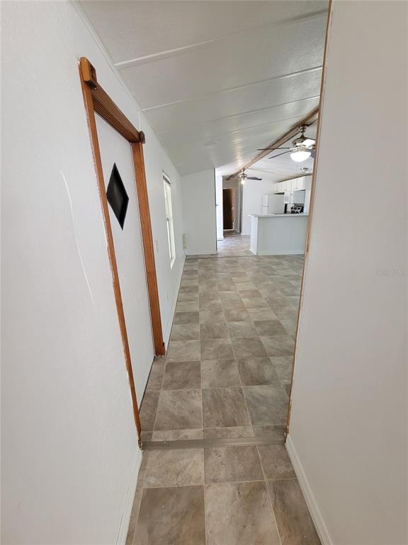 An open-concept living area features tiled flooring, white walls, and two ceiling fans — 14737 BOLAND, SPRING HILL, FL