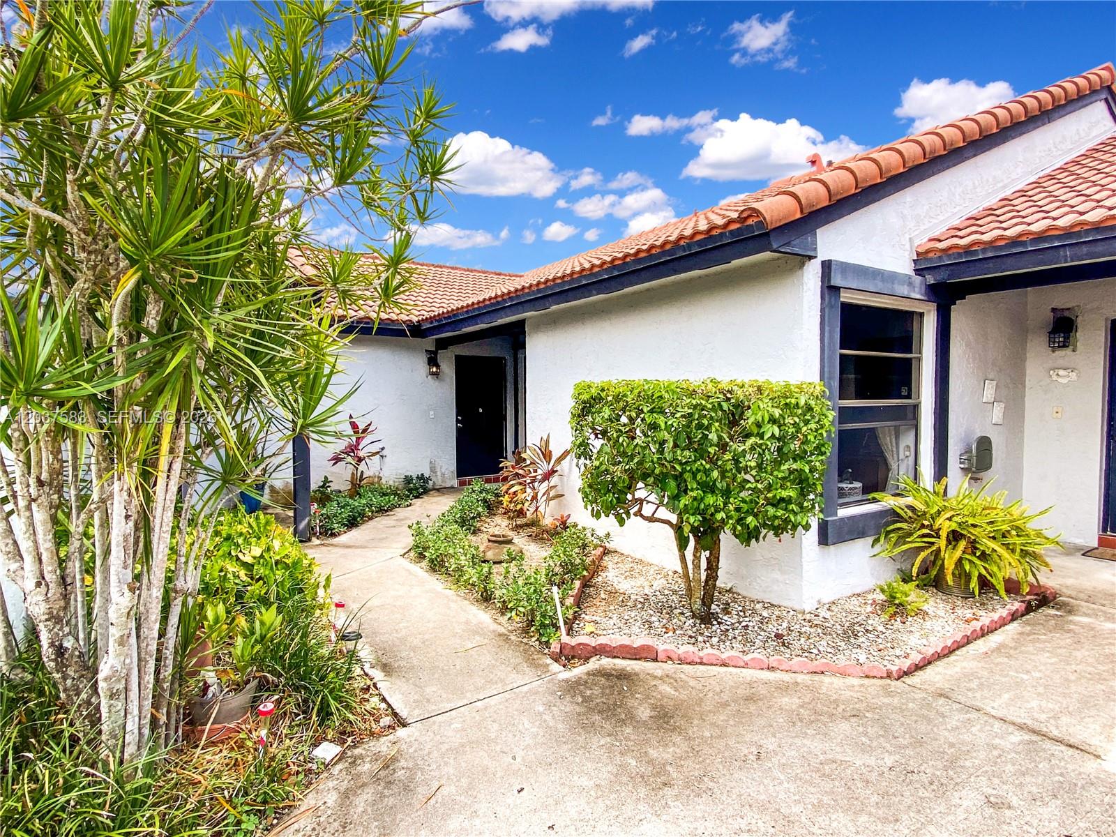 A concrete walkway leads to the front entrance of a house with a tiled roof — 14980 SW 48th Ter # 28F, Miami FL 33185, MIAMI, FL