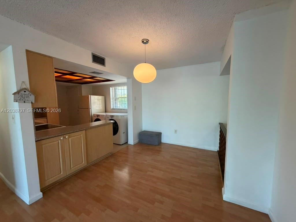 A kitchen with light wood cabinets and a dining area with wood-look flooring — 8775 Park Blvd # 318, Miami FL 33172, MIAMI, FL