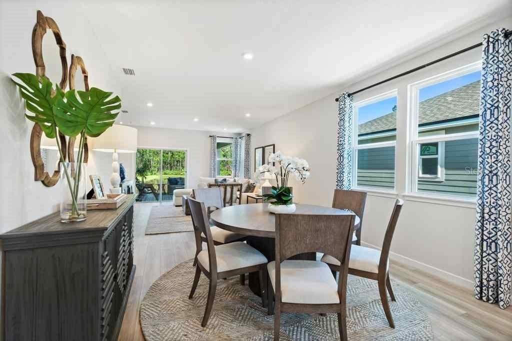 A dining area with a round wooden table, chairs, and a sideboard in an open room — 1357 RIBBON PLACE, PALM COAST, FL