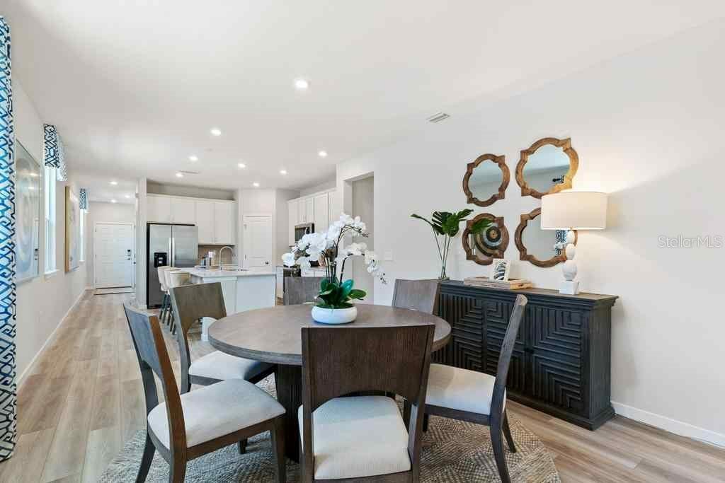 A dining area with a round wooden table, chairs, and a sideboard with wall mirrors — 1357 RIBBON PLACE, PALM COAST, FL