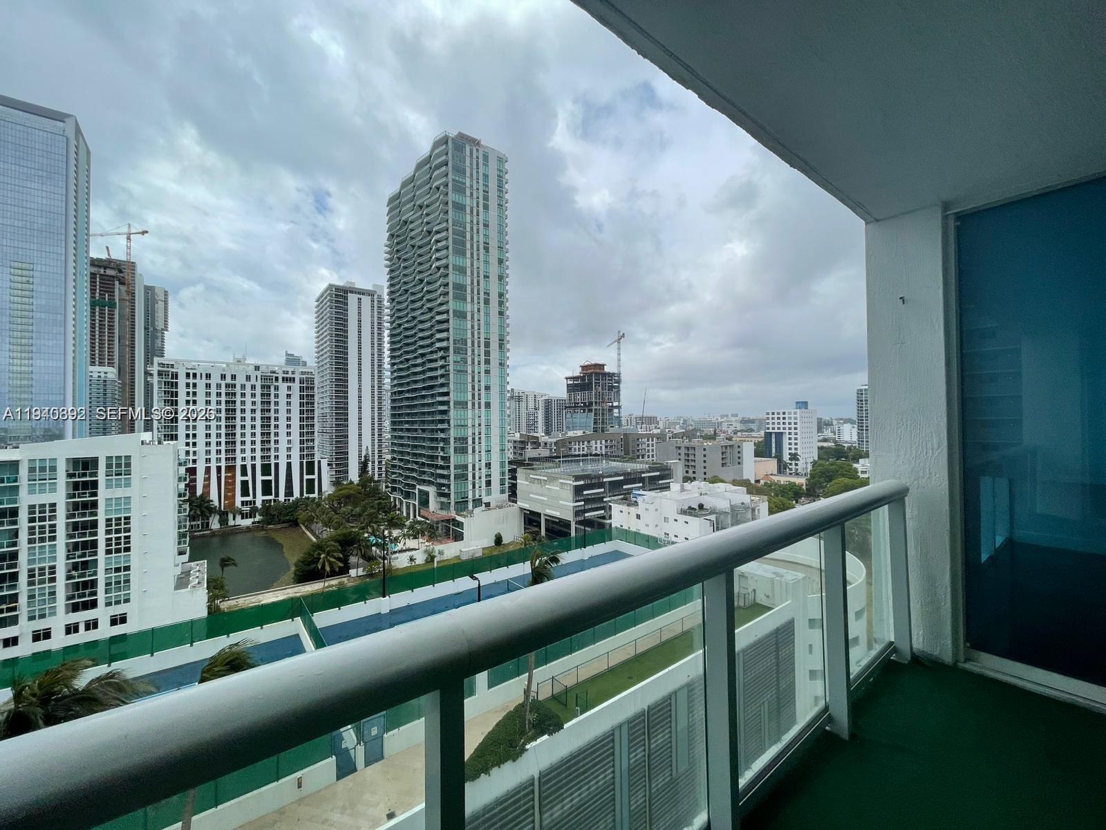 A balcony view overlooks a tennis court, a small pond, and several high-rise apartment buildings — 480 NE 30th St # 1403, Miami FL 33137, MIAMI, FL