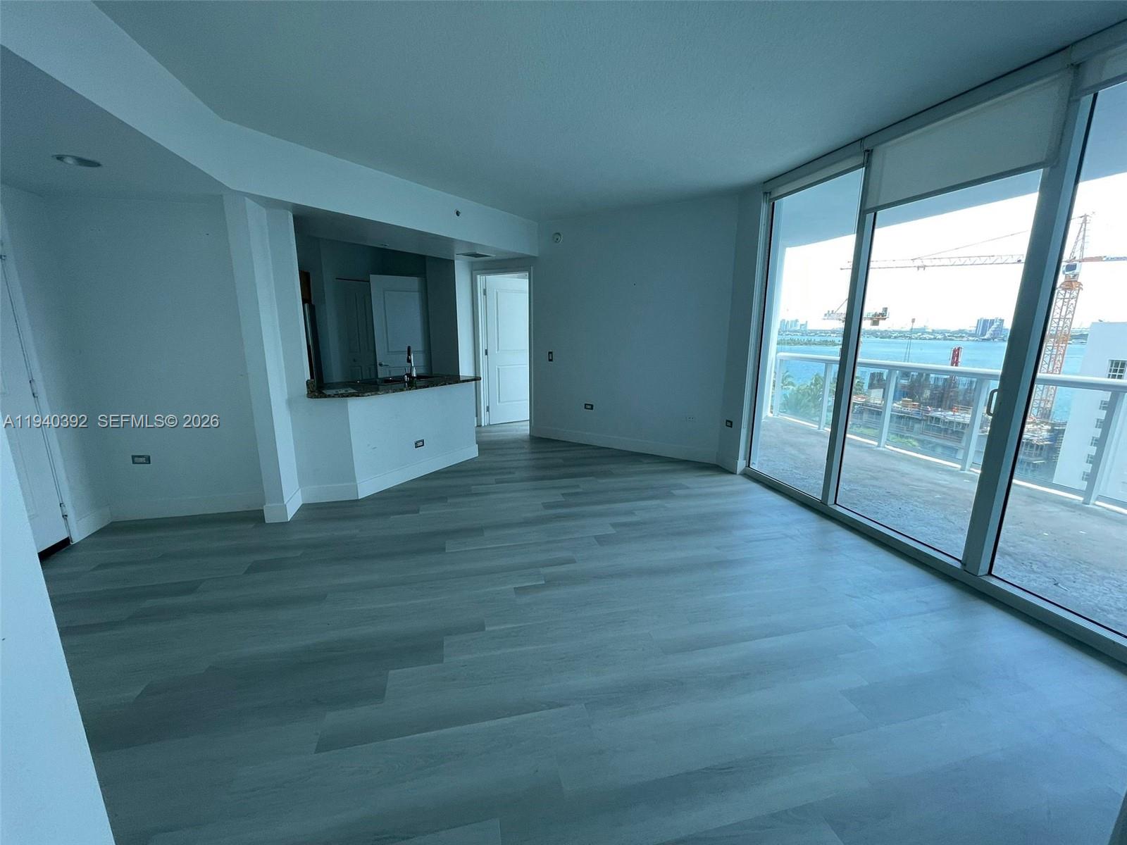 This living area features light wood-look flooring, a kitchen pass-through, and floor-to-ceiling windows — 480 NE 30th St # 1403, Miami FL 33137, MIAMI, FL
