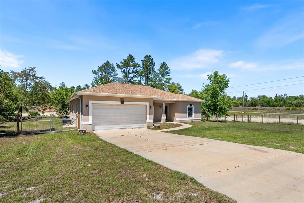 A single-story house with a tan stucco exterior, a two-car garage, and a concrete driveway — 13391 RUFFED GROUSE ROAD, WEEKI WACHEE, FL