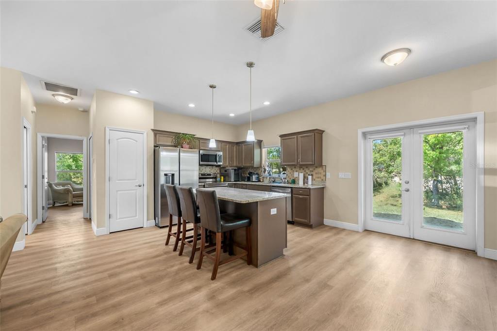 A kitchen with brown cabinets, granite countertops, a center island, and light wood-look flooring — 13391 RUFFED GROUSE ROAD, WEEKI WACHEE, FL