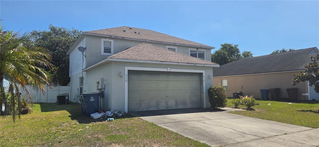 A two-story house with a beige stucco exterior, a two-car garage, and a concrete driveway — 810 DENGAR AVENUE, HAINES CITY, FL