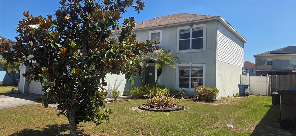 A two-story house with a light-colored exterior, a front yard, and a large magnolia tree — 810 DENGAR AVENUE, HAINES CITY, FL