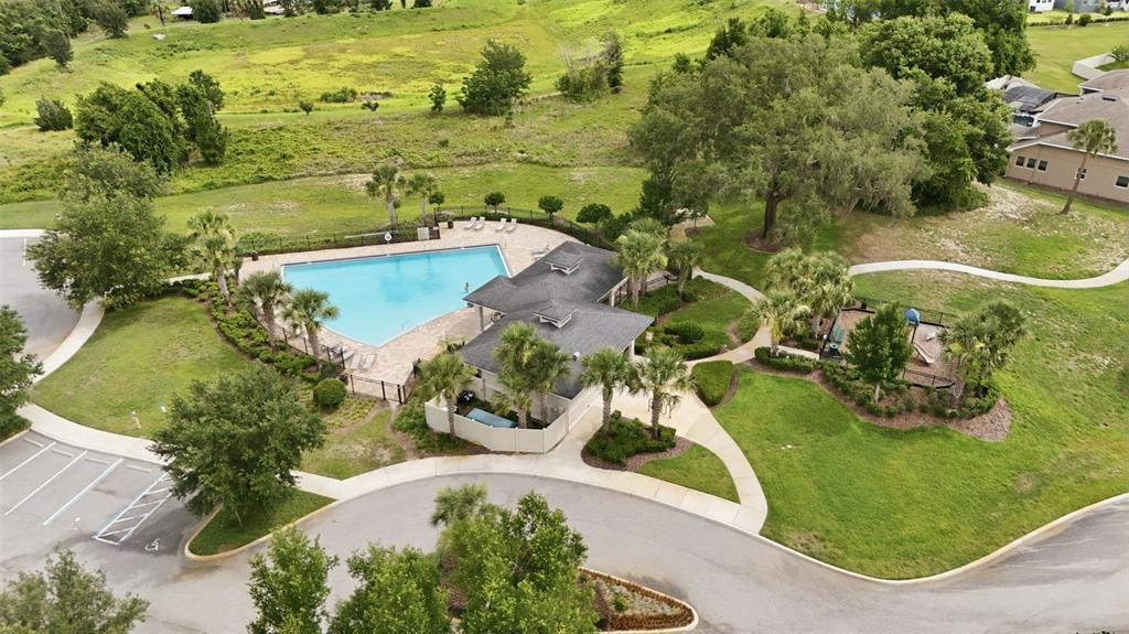 An aerial view shows a community swimming pool, clubhouse, and playground surrounded by landscaped grounds — 16716 ABBEY HILL COURT, CLERMONT, FL