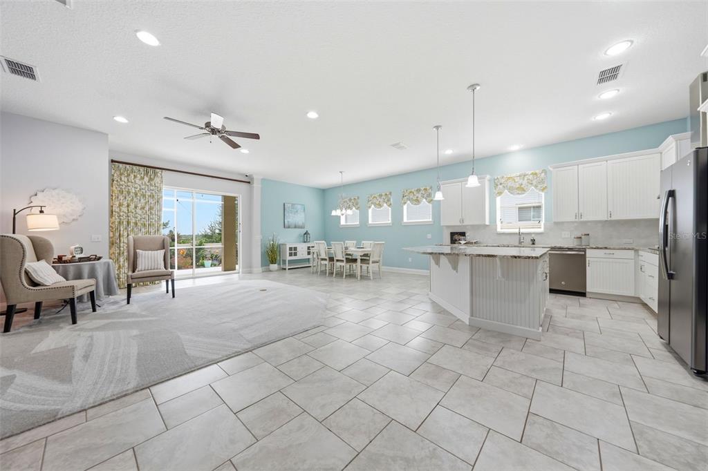 An open-concept kitchen and living area features light blue walls, tile flooring, and white cabinetry — 16716 ABBEY HILL COURT, CLERMONT, FL