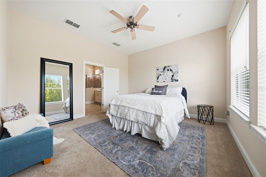 A bedroom features a bed, a blue armchair, a floor mirror, and a ceiling fan — 16716 ABBEY HILL COURT, CLERMONT, FL