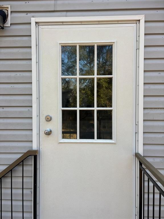 A white exterior door with a nine-pane window sits between gray horizontal siding — 10405 JUNGLE STREET, NEW PORT RICHEY, FL