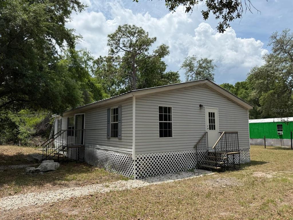 A light gray manufactured home with white lattice skirting and two sets of metal stairs — 10405 JUNGLE STREET, NEW PORT RICHEY, FL
